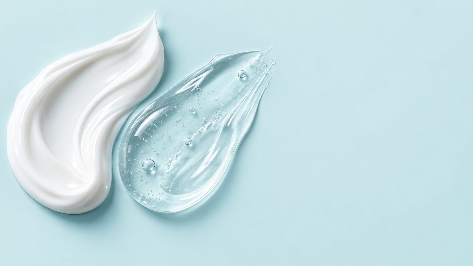Swirls of white cream and clear gel on a pale aqua surface